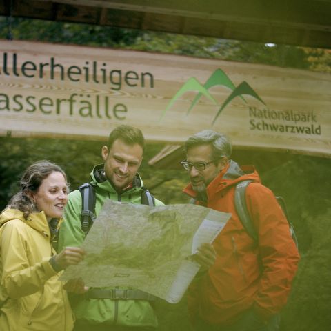 Eine Wandergruppe an den Allerheiligen Wasserfällen im Nationalpark Schwarzwald bei der Tourplanung.
