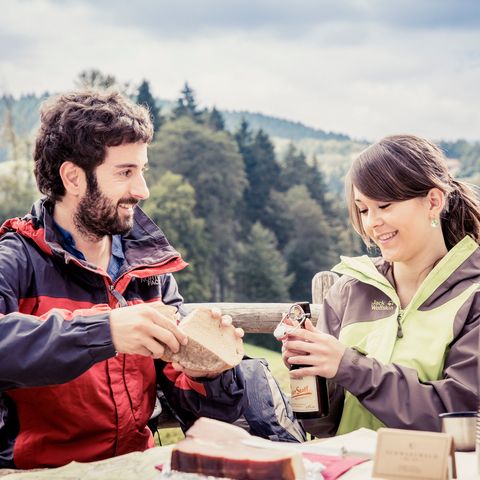 Junges Pärchen genießt ein leckeres Vesper während einer Wanderung mit Schwarzwald Plus.