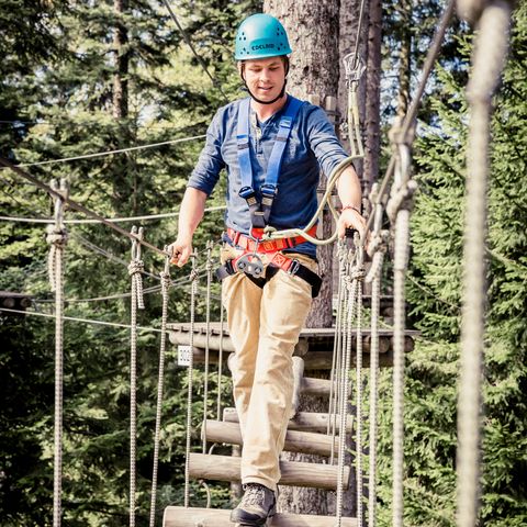 Mit angelegter Sicherheitsausrüstung bewältigt der Kletterer im Erlebnis-Kletterwald Enzklösterle die Hindernisse des Parcours.