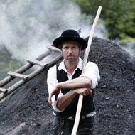 Köhler Thomas Faisst vor dem qualmenden Kohlenmeiler in Baiersbronn.