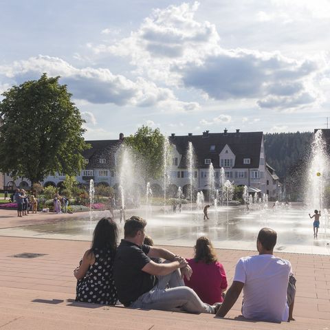 Eine Gruppe genießt den Sommer an den Fontänen neben der Stadtkirche auf dem Marktplatz Freudenstadt.